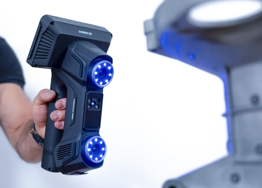 FreeScan Omni Series Wireless 3D Scanning with Hot-Swappable Batteries Operator holding FreeScan Omni wireless metrology 3D scanner with illuminated blue scanning optics near an industrial component